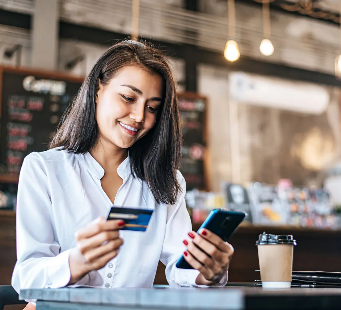 Pay for goods by credit card through a smartphone in a coffee shop.